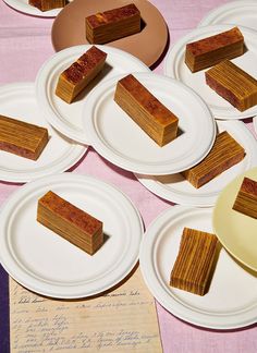 several slices of cake sitting on top of white plates next to paper plates with writing on them