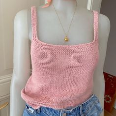 a mannequin wearing a pink sweater and denim shorts with a necklace on it