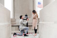 a man kneeling down next to a woman in front of a building with petals on the ground