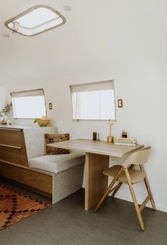 a room with a table, chair and couch in it next to a rug on the floor