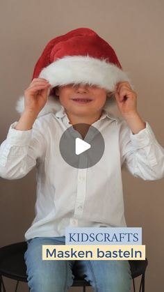 a young boy wearing a santa hat while sitting on top of a chair with his hands behind his head