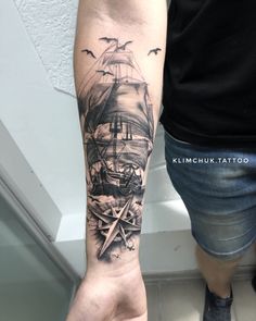 a man's arm with a ship tattoo on it