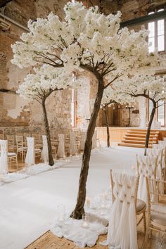 a tree with white flowers is in the middle of a room filled with chairs and tables