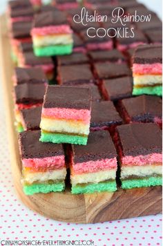 a wooden cutting board topped with rainbow cookies