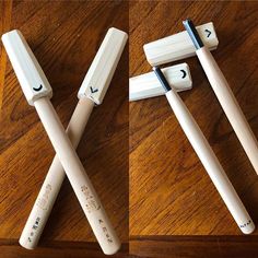 three toothbrushes with faces drawn on them sitting on top of a wooden table