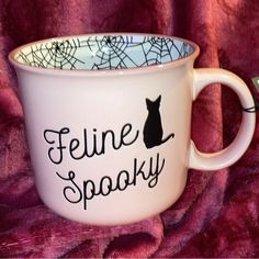 a white coffee cup with a black cat on it and the words feline spooky