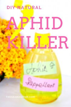 a yellow bottle filled with liquid sitting on top of a table next to some flowers