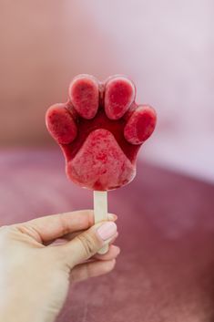 a person is holding a popsicle with some red stuff on it's tip