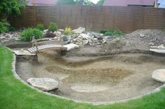 an outdoor area with rocks, grass and a wooden bench in the middle of it