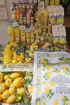 there are many lemons on display at the market table with juice bottles and tea towels