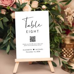 a table sign sitting on top of a wooden easel next to flowers and candles