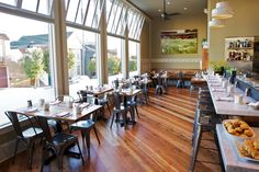 an empty restaurant with wooden floors and large windows