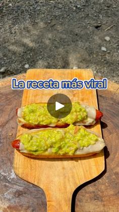 two hotdogs with guacamole and relish on a wooden board