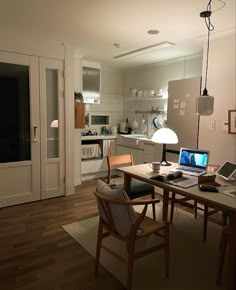 an open laptop computer sitting on top of a wooden table in a living room next to a kitchen