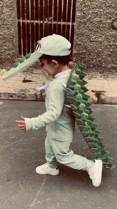 a young boy is walking down the street with a paper hat on his head