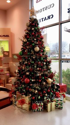 a decorated christmas tree sitting in front of a window next to boxes and wrapped presents