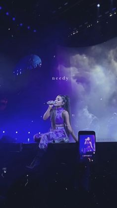 a woman sitting on top of a stage holding a cell phone up to her ear