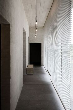 an empty hallway with blinds on the wall and benches in the middle between two walls