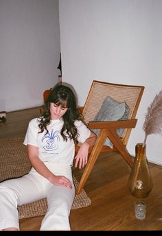 a woman sitting on the floor next to a chair