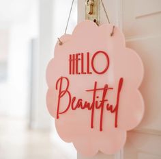 a pink sign that says hello beautiful hanging from a door