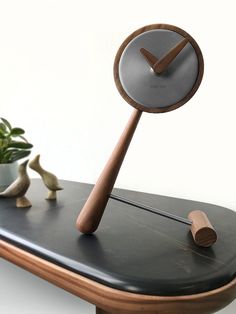 a clock sitting on top of a table next to a potted plant and two small birds