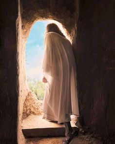 a man dressed in white standing at the entrance to a cave