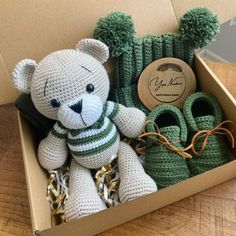 a crocheted teddy bear sitting in a box with slippers on the floor