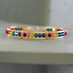 Indulge in the whimsical beauty of our handcrafted wire-wrapped bracelet in 14kt gold filled wire, adorned with rainbow crystal beads that sparkle all the way around your wrist. Each bead showcases a burst of vivid color, creating a joyous and celebratory accessory that instantly uplifts your spirits.  The fashionable design of this bracelet embraces the empowering message of love, pride, and diversity. Crafted as always with meticulous attention to detail, it exudes a stylish charm that brillia Handmade Bohemian 14k Gold-filled Bracelet, Handmade 14k Gold-filled Bohemian Bracelet, Handmade 14k Gold Filled Bohemian Bracelet, Adjustable Wire Wrapped Crystal Bangle Bracelet, Multicolor Wire Wrapped Bangle Bracelets, Multicolor Wire Wrapped Bangle Bracelet, Adjustable Wire Wrapped Wrap Bracelet Bangle, Adjustable Wire Wrapped Wrap Bracelet, Adjustable Rainbow Bangle