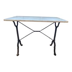 a white marble top table with wrought iron legs and an iron base, against a white background