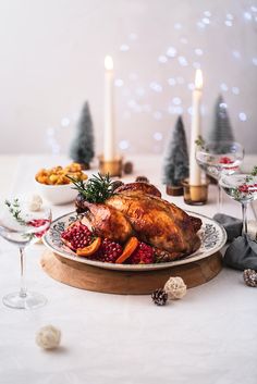 a roasted turkey on a platter with cranberries, oranges and pine cones