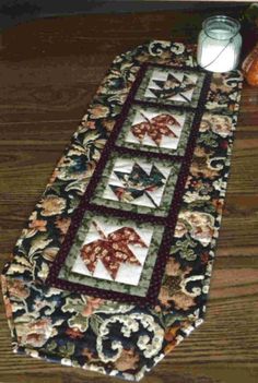 a table runner with elephants on it and a candle in the middle next to it