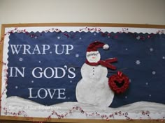 a snowman with a red hat and scarf on it's head is standing in front of a sign that says wrap up in god's love