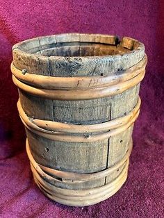 an old wooden basket sitting on top of a purple blanket