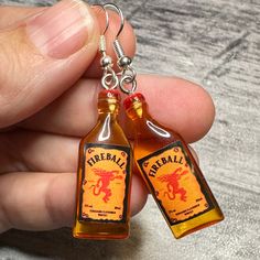 two miniature bottles are being held in the palm of a person's left hand