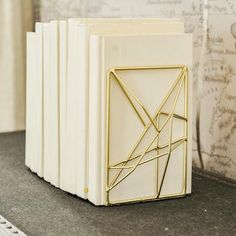 a set of four white books sitting on top of a table next to a wall