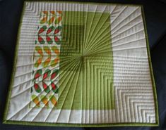 a green and white quilted table topper with an orange flower design on it