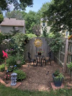 a small backyard with a table and chairs in the middle, surrounded by plants and trees