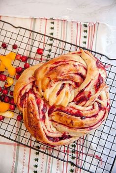 a pastry sitting on top of a cooling rack next to oranges and cherries