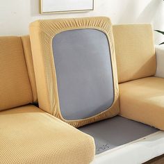 a couch with a cushion on it and a plant in the corner next to it