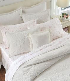 a bed with white comforter and pillows on top of it