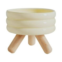 a white ceramic bowl with wooden legs on a white background