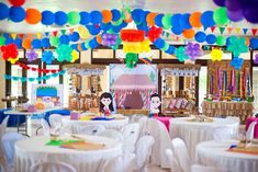 a room filled with lots of tables covered in white tablecloths and colorful balloons