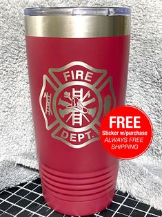 a red fire department tumbler cup sitting on top of a table next to a white towel