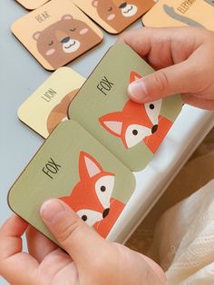 a person is holding up some cards with animals on them and the words fox are in front of them