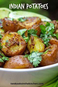 a white bowl filled with potatoes and cilantro on top of a green cloth