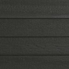 the side of a black wooden building with white trim and wood grains on it