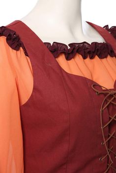 an orange and red dress with ruffles on the neckline is shown in front of a mannequin's head