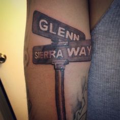 a close up of a person's arm with a cross and street signs on it