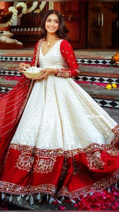 a woman in a white and red wedding dress standing on steps with flowers around her