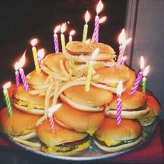 a birthday cake made to look like hamburgers with lit candles on them and sandwiches in the middle